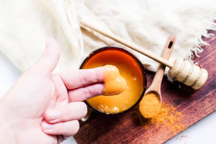 Using the finger tips to scoop up a small amount of the face mask out of the container.