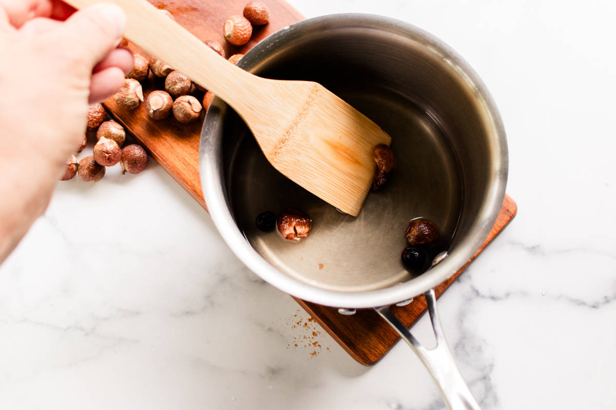 Crushing up the soapnuts in the boiling water with a wooden spatula.