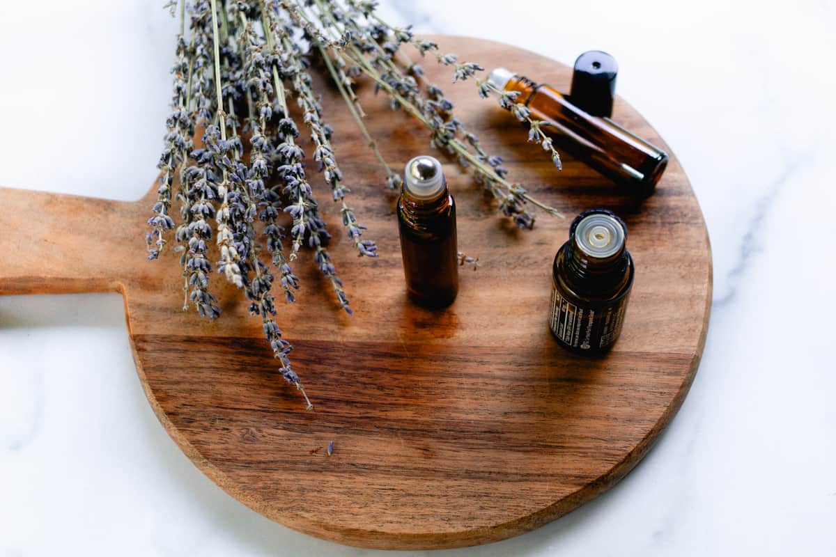 10mL roller bottle of homemade lip oil on a wooden board with EOs.