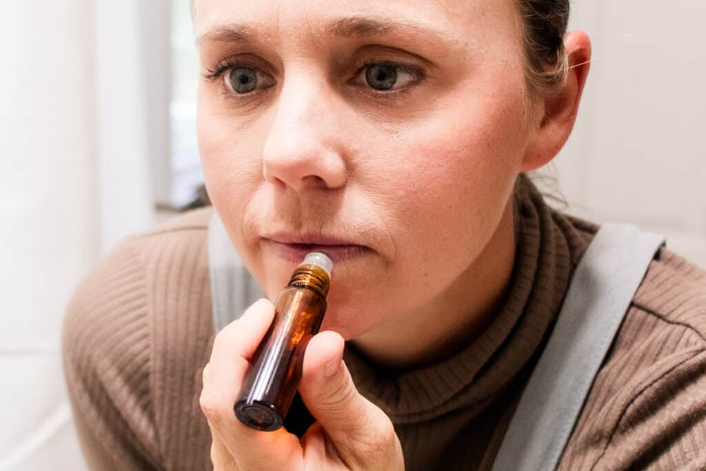 Applying the lip oil gently to the lips. 