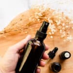 DIY hair perfume being shaken up in a dark colored spray bottle.