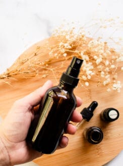 DIY hair perfume being shaken up in a dark colored spray bottle.