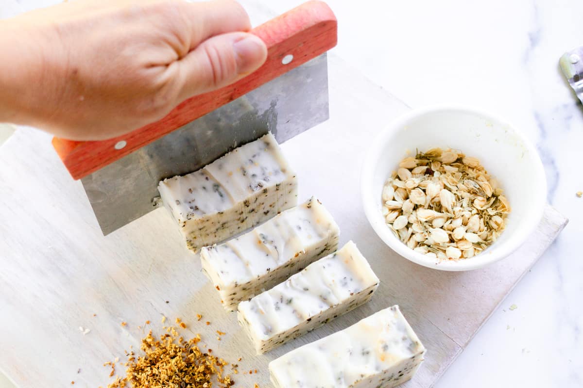 Using a soap knife to cut the herbal soap bars into one inch bars.