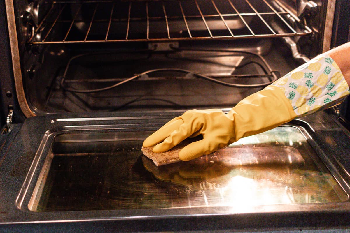 Wiping an oven clean with a sponge after steam cleaning.