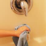 Cleaning the shower faucet of calcium buildup.