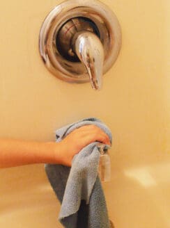 Cleaning the shower faucet of calcium buildup.