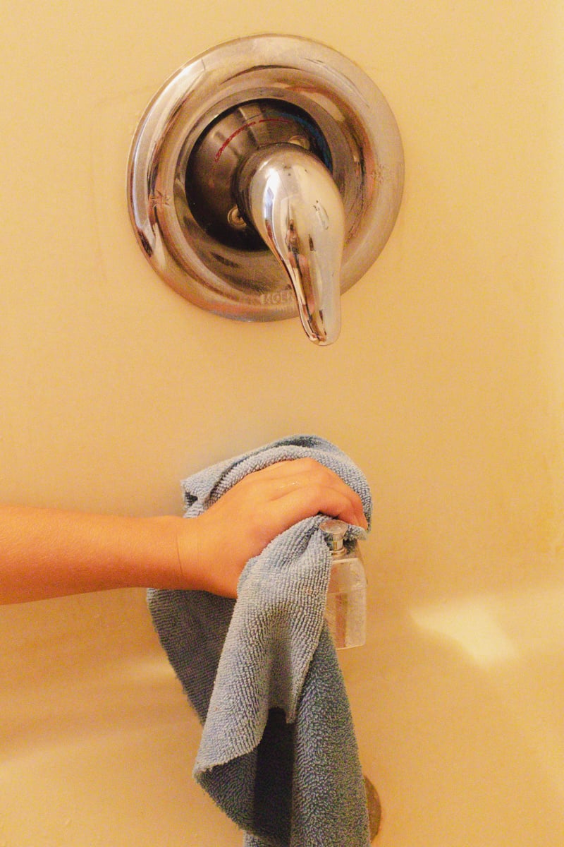 Wiping the white calcium buildup off the faucet for the bath.