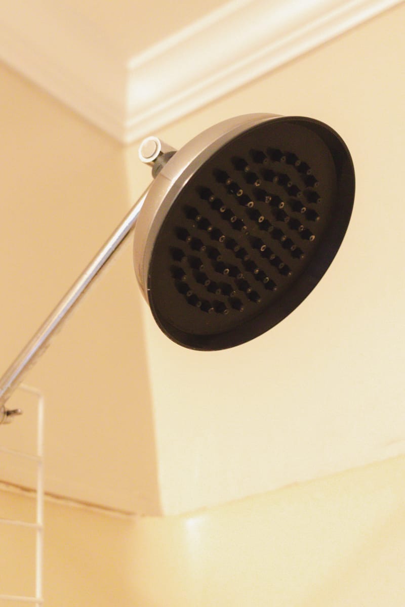 A stainless steel shower head with rubber nozzles after it has been cleaned with vinegar to remove the calcium buildup.
