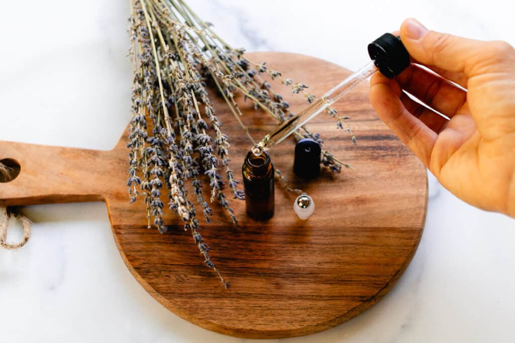 Adding essential oils to a roller bottle with a dropper.