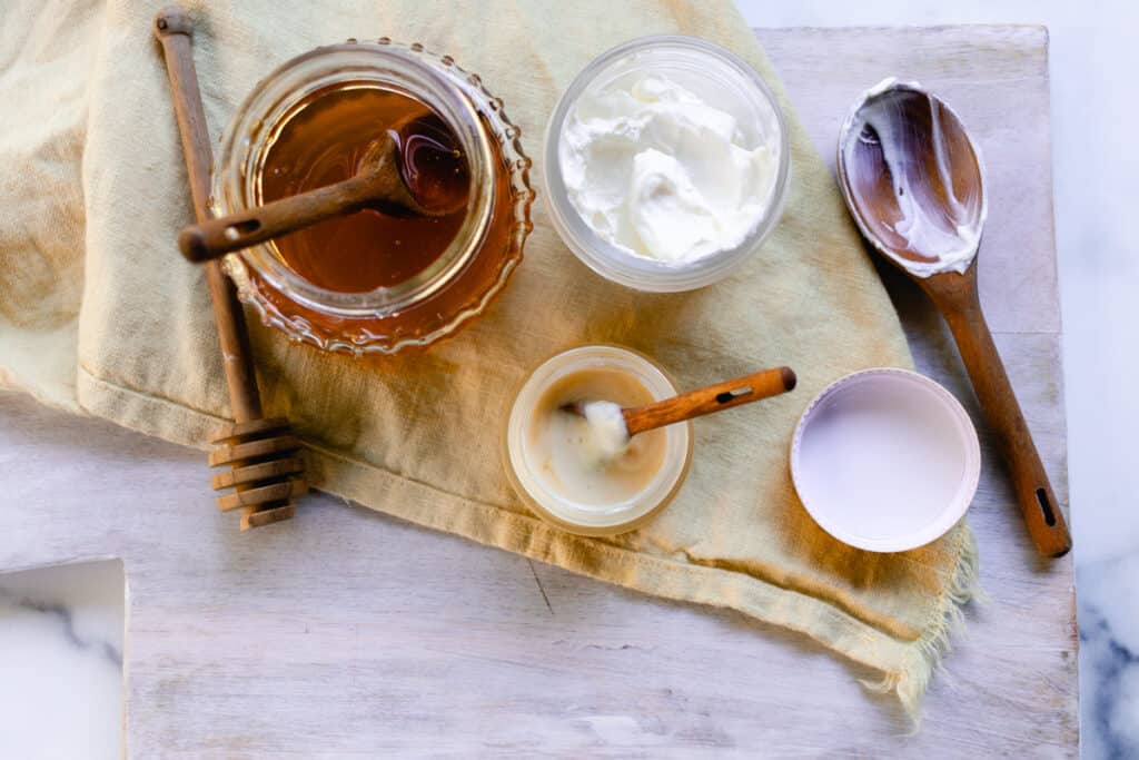 All the ingredients needed to make a exfoliating lip mask on a white wooden table. 