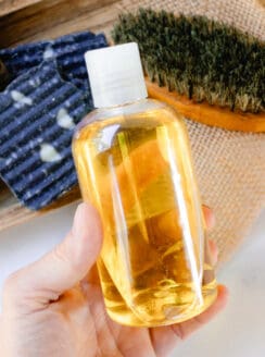 Holding a homemade pre shave oil thats in a clear bottle ready to apply to the skin.