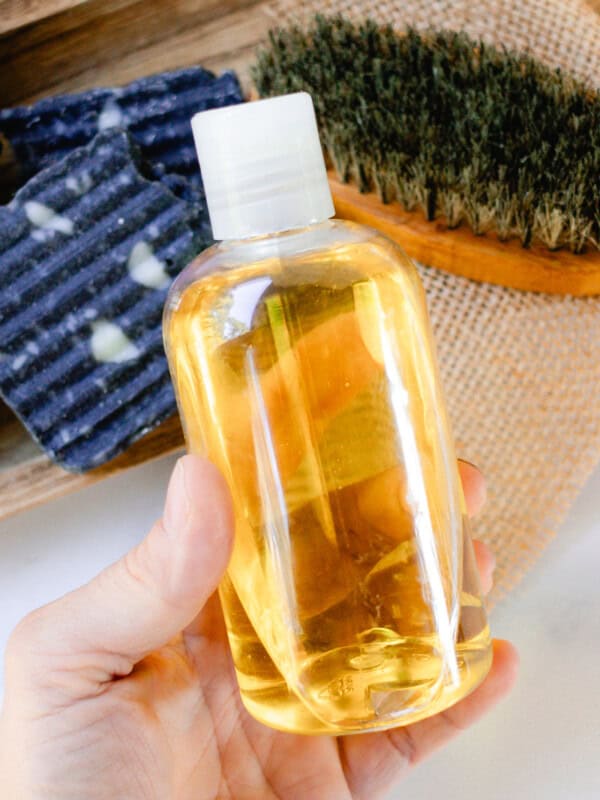 Holding a homemade pre shave oil thats in a clear bottle ready to apply to the skin.