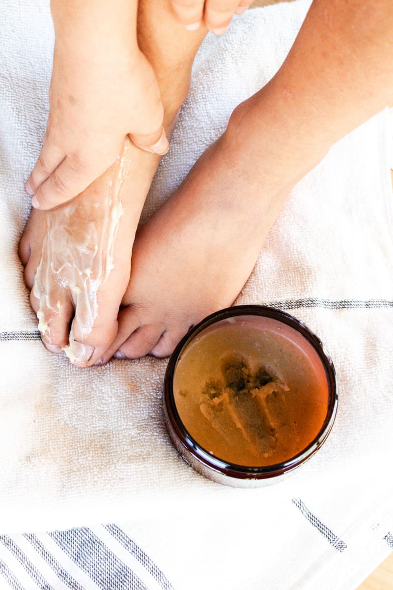 Generously applying the foot mask while resting my feet on a towel to prevent messes.
