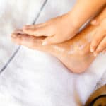 Rubbing a hydrating foot mask onto my feet while they rest on a towel.