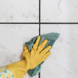 Wiping the grout clean after spraying it with a mold spray.