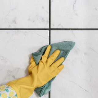 Wiping the grout clean after spraying it with a mold spray.