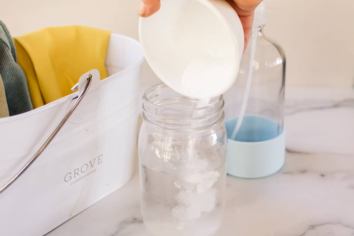 Adding baking soda to water to make a mold spray for tile grout.