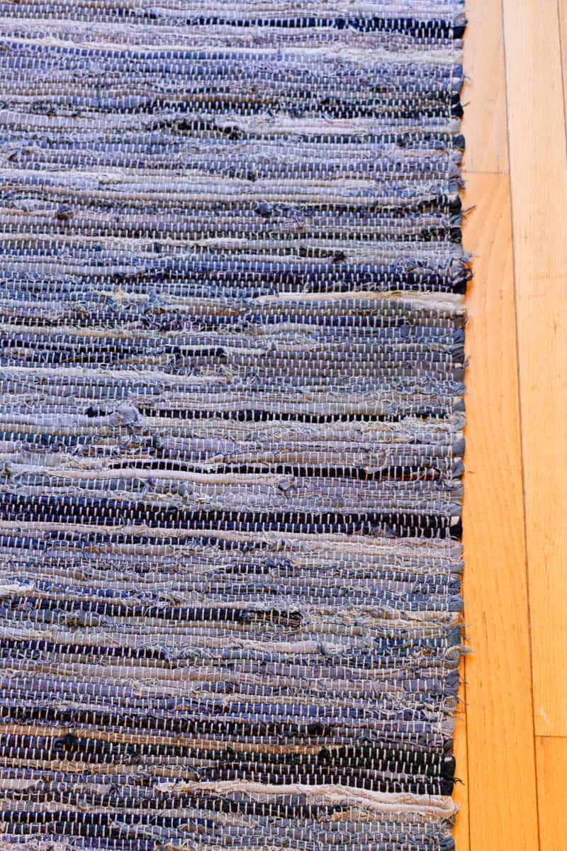 A clean braided rug laying out on a wooden floor.