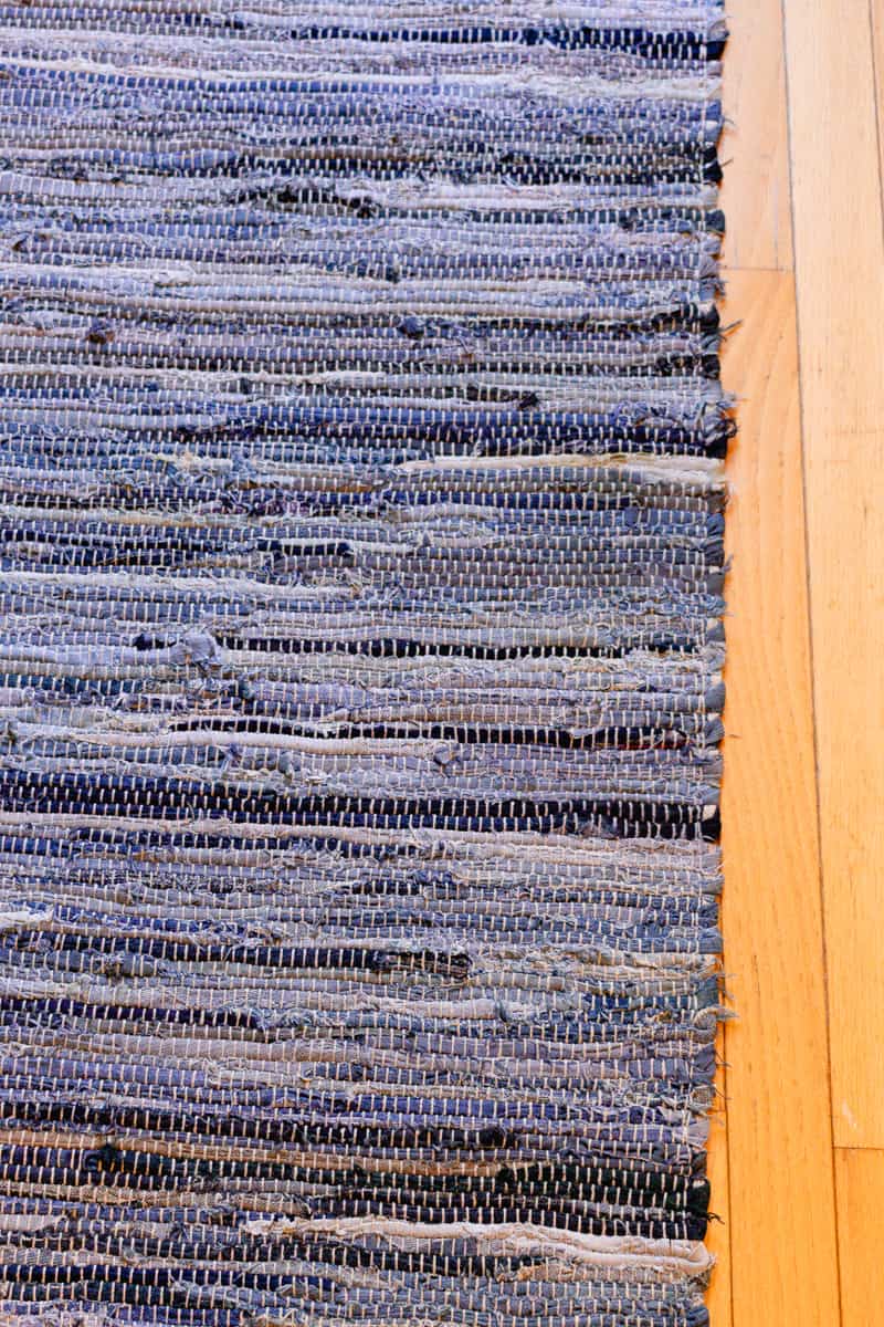 A clean braided rug laying out on a wooden floor.