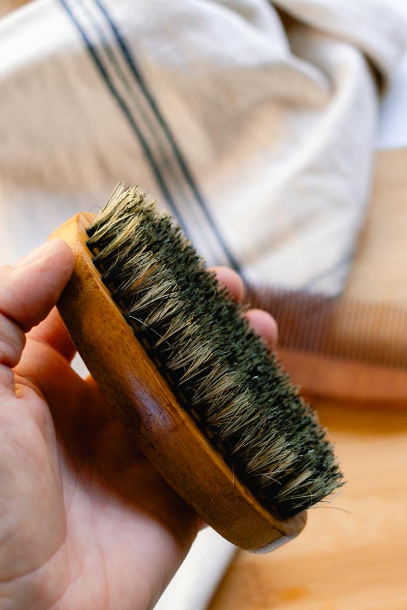 Inspecting the clean beard brush after washing it to check for loose bristles.