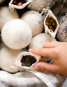 Placing a sachet with dried herbs for wool dryer balls into a basket to help create scent.