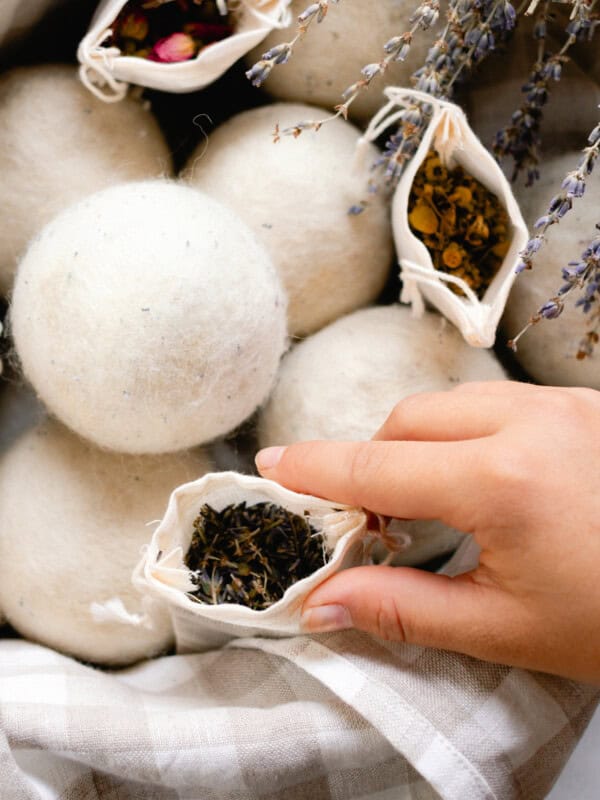 Placing a sachet with dried herbs for wool dryer balls into a basket to help create scent.