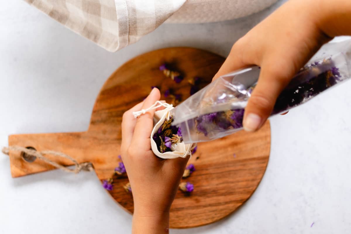 Pouring dried herbs into a muslin bag.