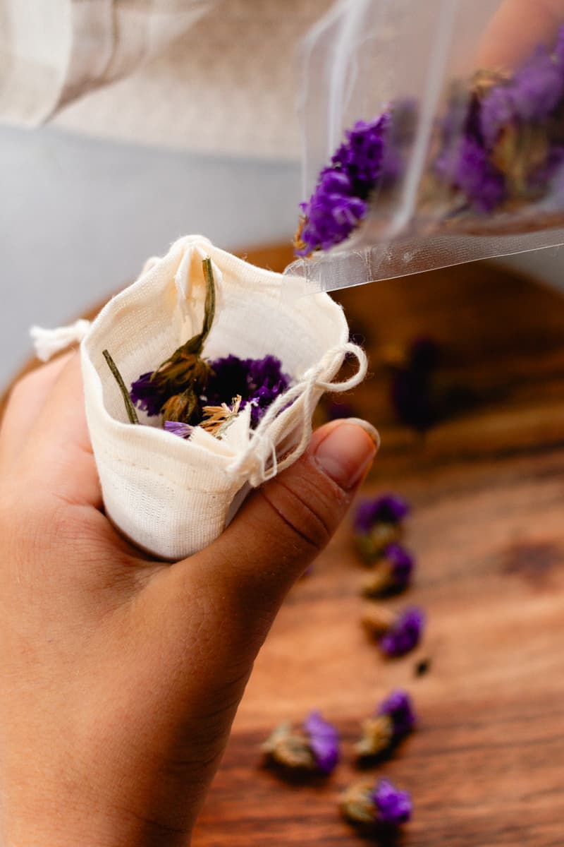 Filling a muslin bag with dried lavender petals to set next to the dryer balls to naturally fragrance them.