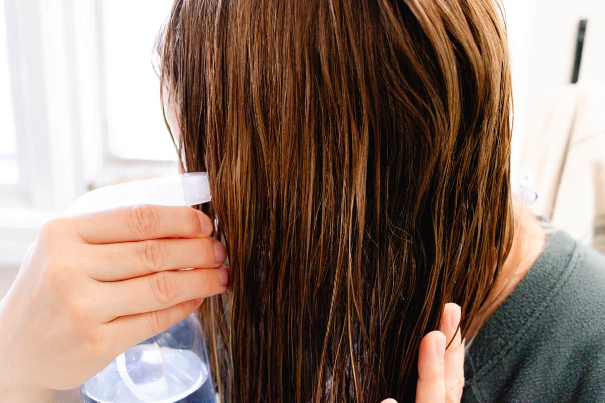 Spraying coconut water into the hair for hydration.