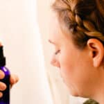 Spraying face mist onto my skin to hydrate it.