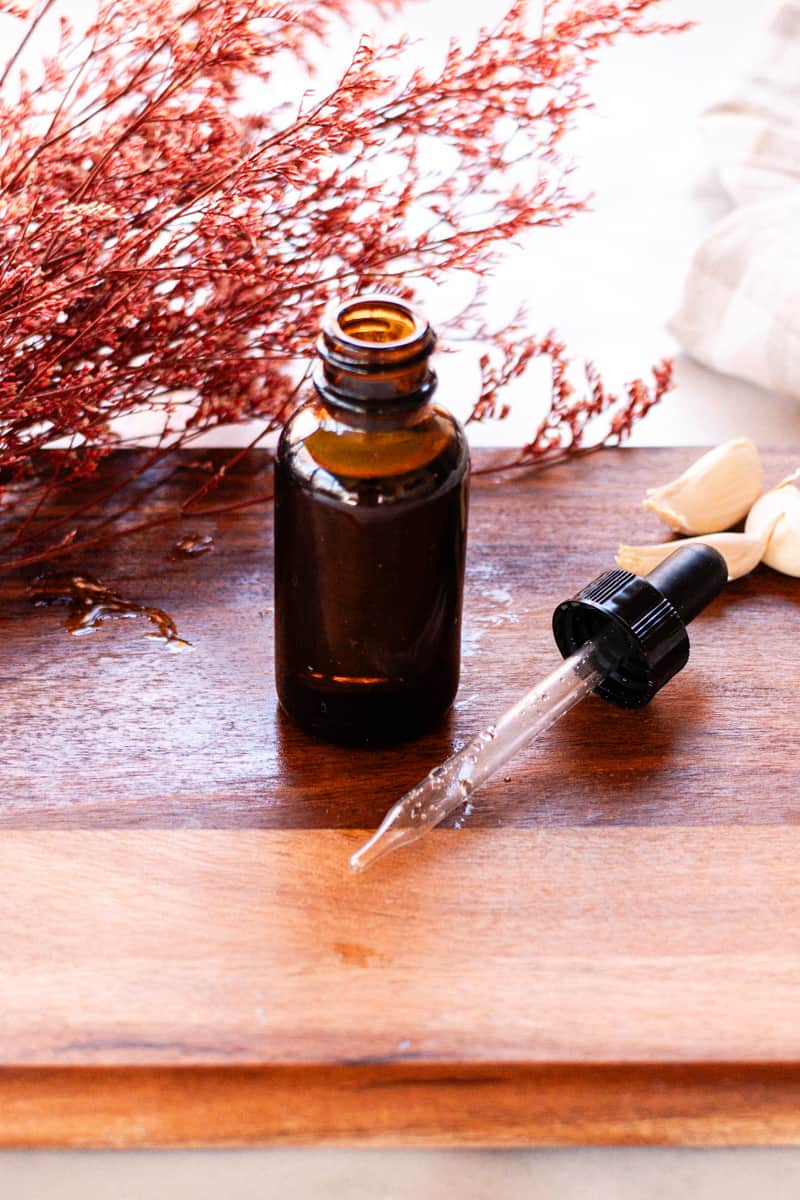 A DIY nail growth serum in a glass dropper bottle on a wooden table.