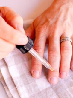 Applying the DIY nail growth serum to the base of the fingernails with a dropper.