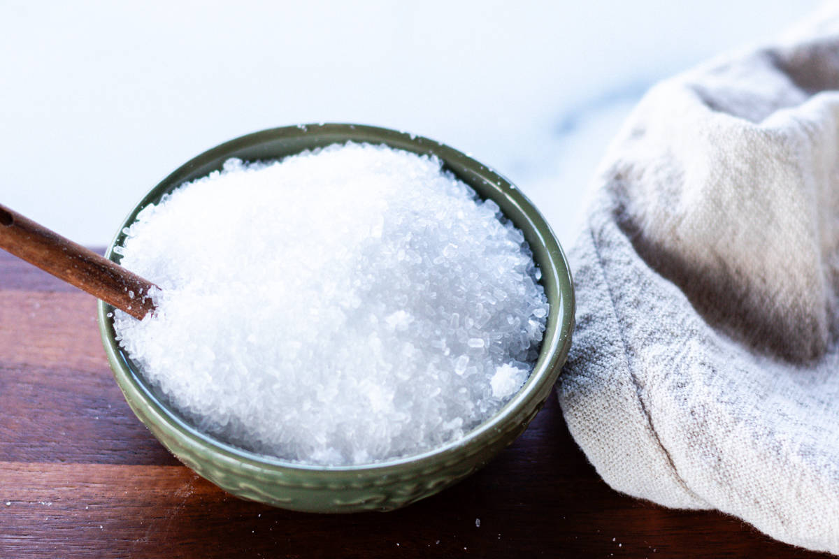 A small green bowl of epsom salts on a wooden tray.