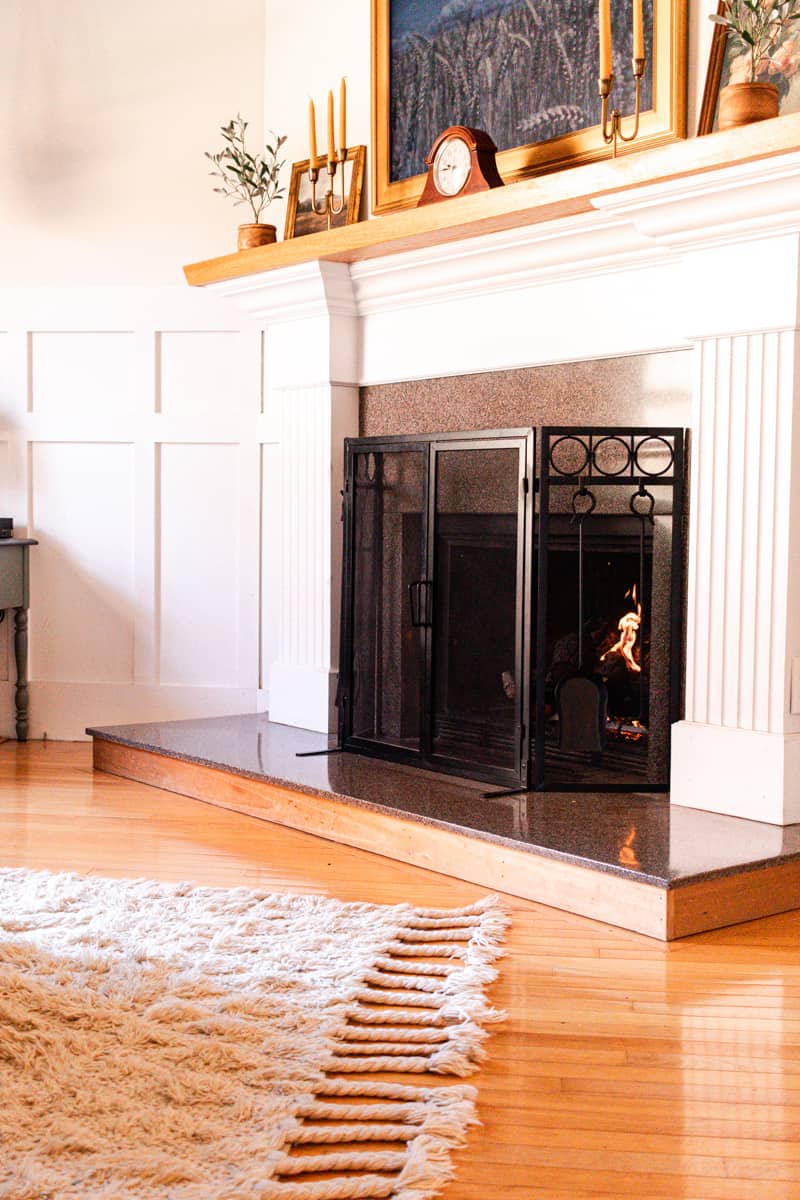 A shot of a decorated fireplace with a beautiful frame tv above it and clean stain free rug at the base.