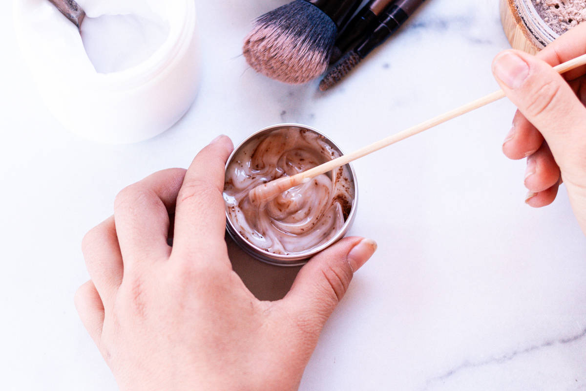 Stirring the cocoa powder into the lotion with a wooden stirrer to make a foundation.