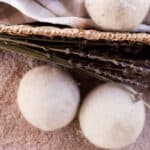 Several wool dryer balls, some in a basket and some on the carpet next to it.