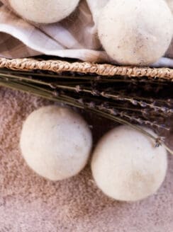 Several wool dryer balls, some in a basket and some on the carpet next to it.