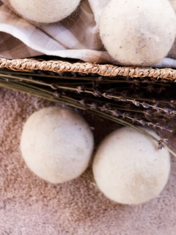 Several wool dryer balls, some in a basket and some on the carpet next to it.
