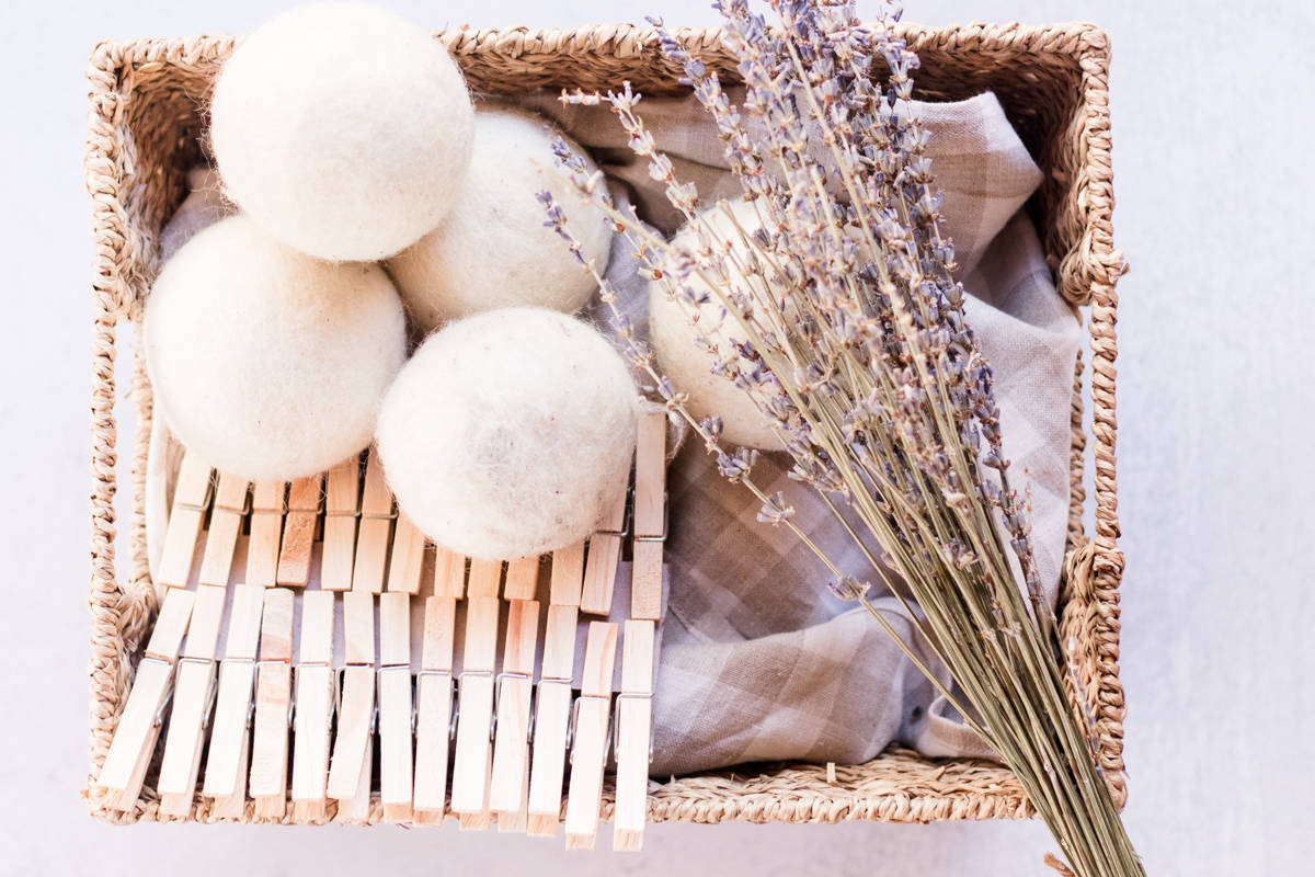 Wool dryer balls in a basket with a towel, clothes pins and a few sprigs of lavender.