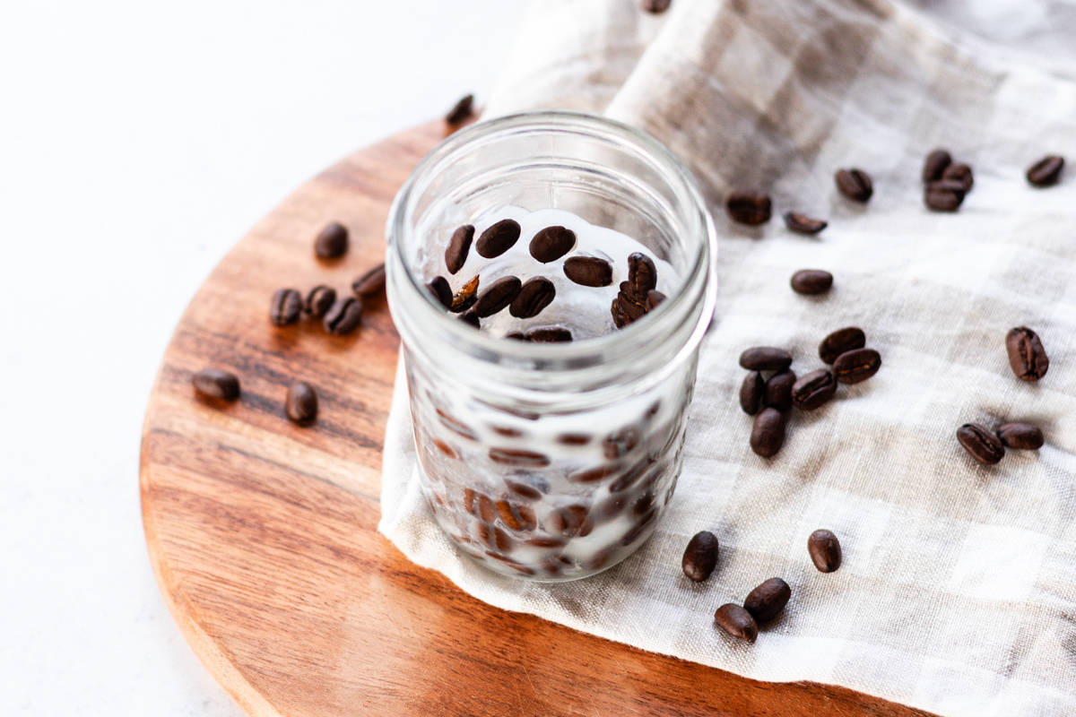 Pressing the coffee beans against the side of the jar.