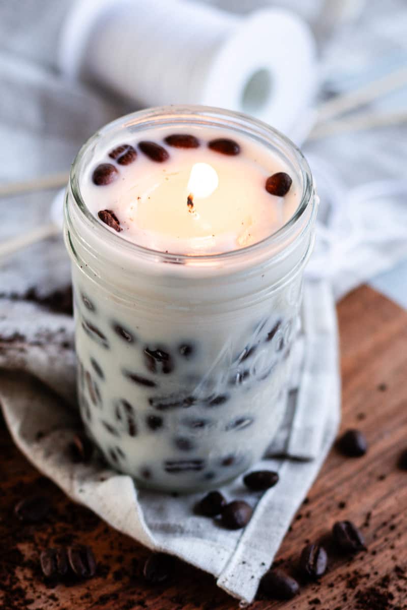 Lighting the DIY coffee candle and placing it in the center of a table with whole coffee beans spread around it.