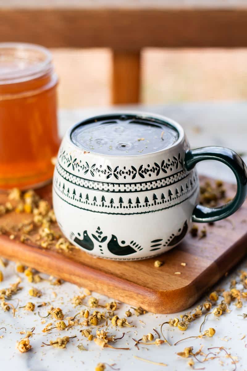 A hand soak made from chamomile tea brewing in a decorated mug.
