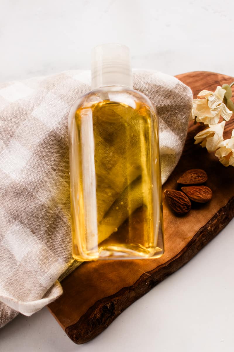 The DIY shower oil in a reusable plastic bottle on a checkered towel.