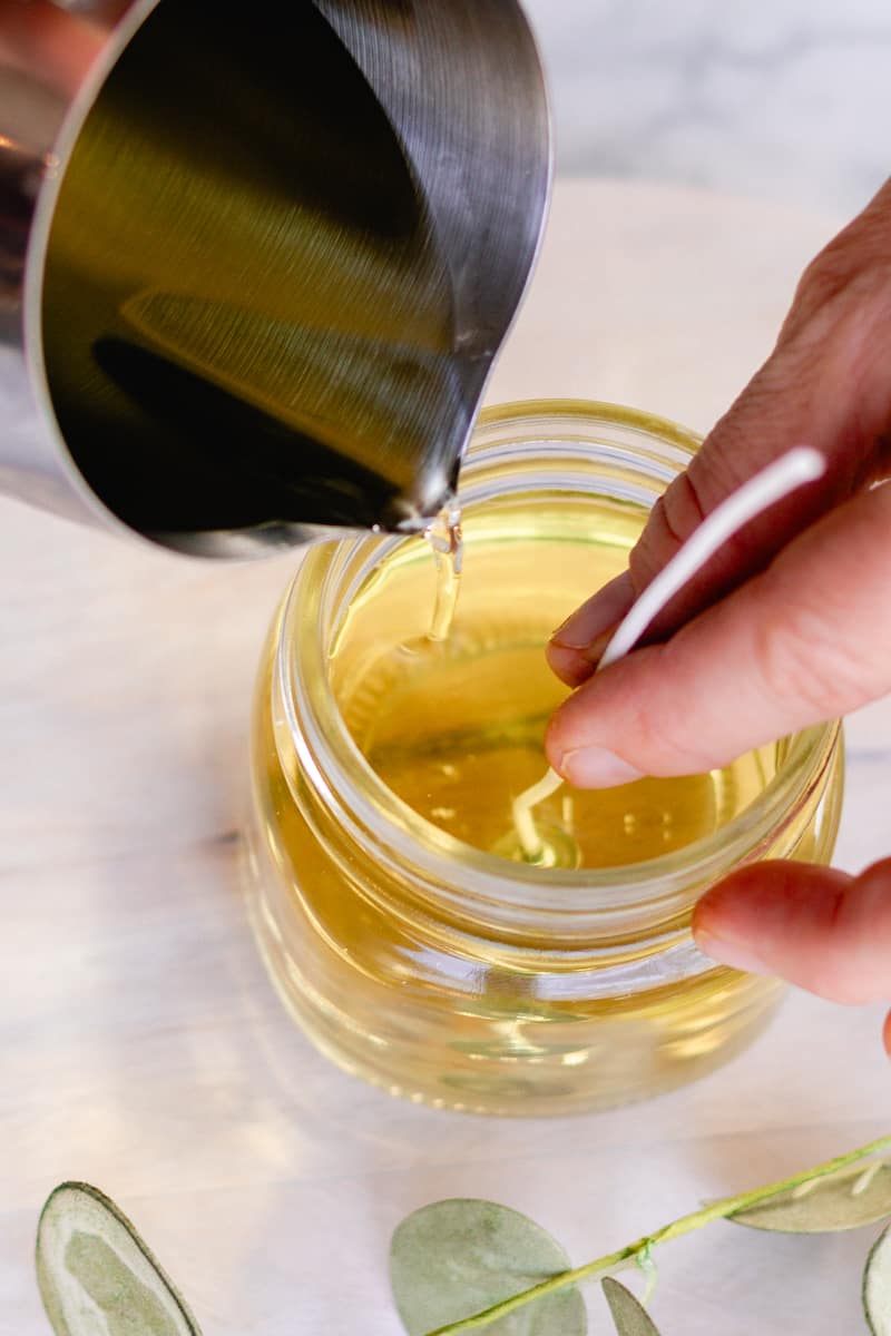 Pouring the melted soy wax into the candle jar.