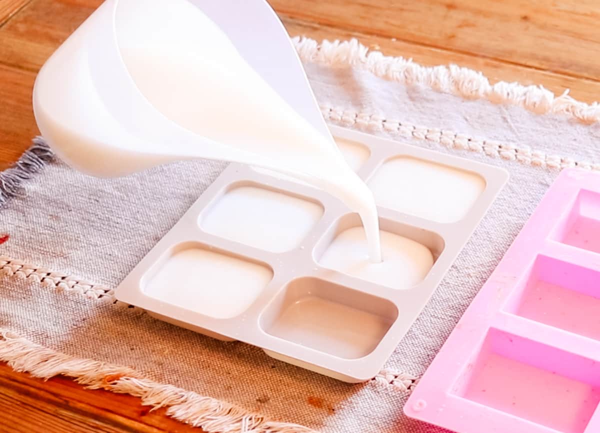 Pouring the melted cold process coconut oil soap into the soap molds so that they can cure and harden.