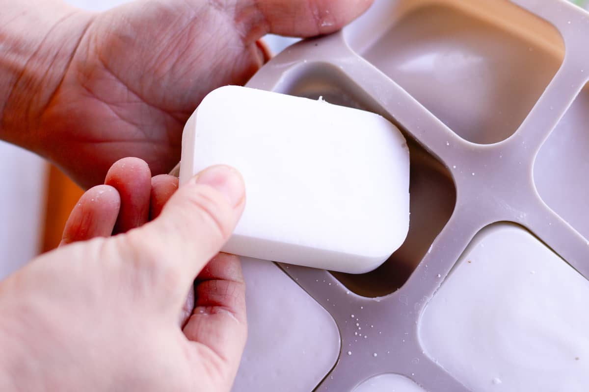 Pulling the hardened, but not yet cured soap bars out of the molds so that they can cure properly.