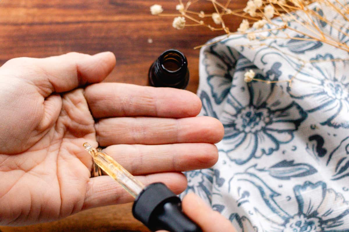 Homemade hair growth oil being dispensed into my hand before working it into the strands.