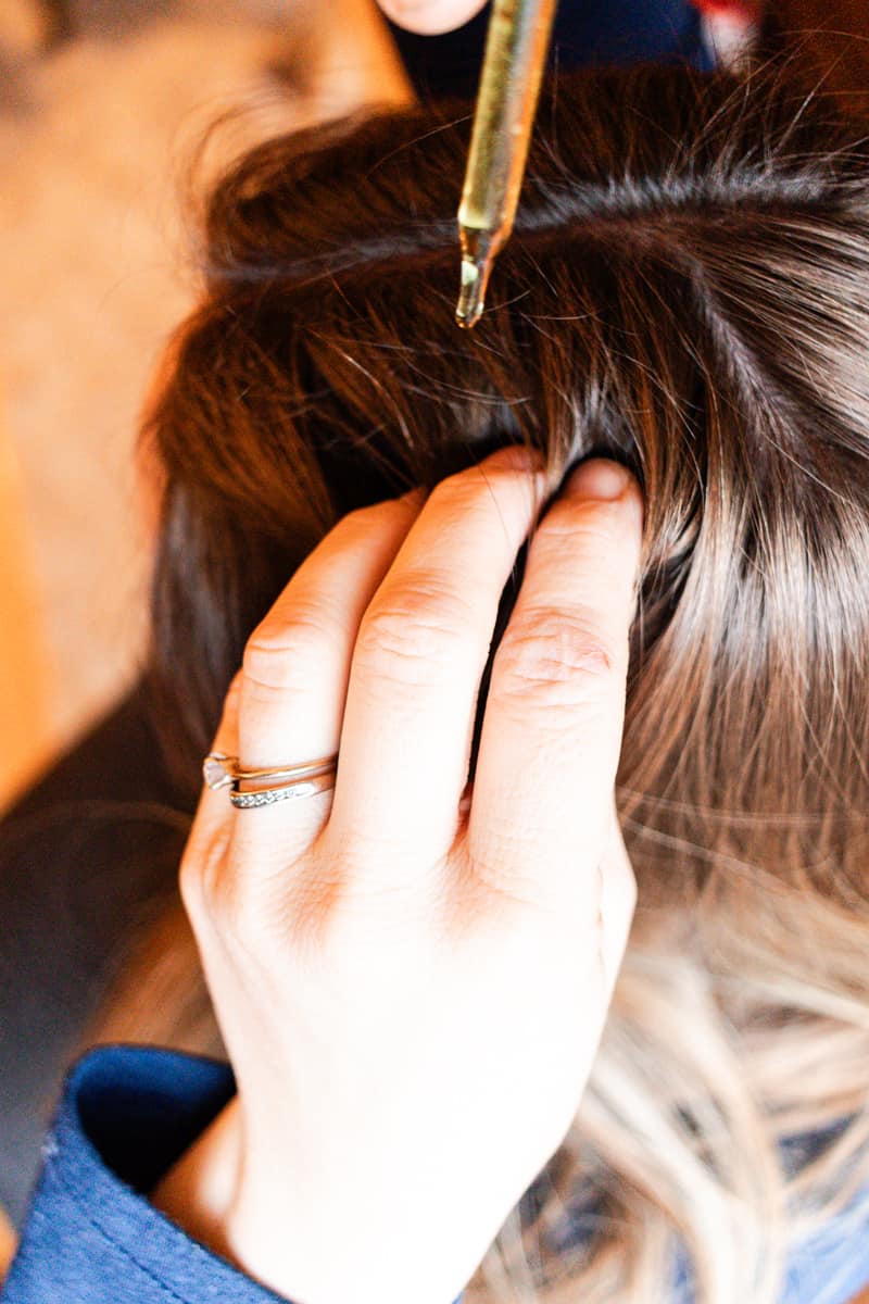 Using a dropper to apply the homemade hair growth oil to my hair.