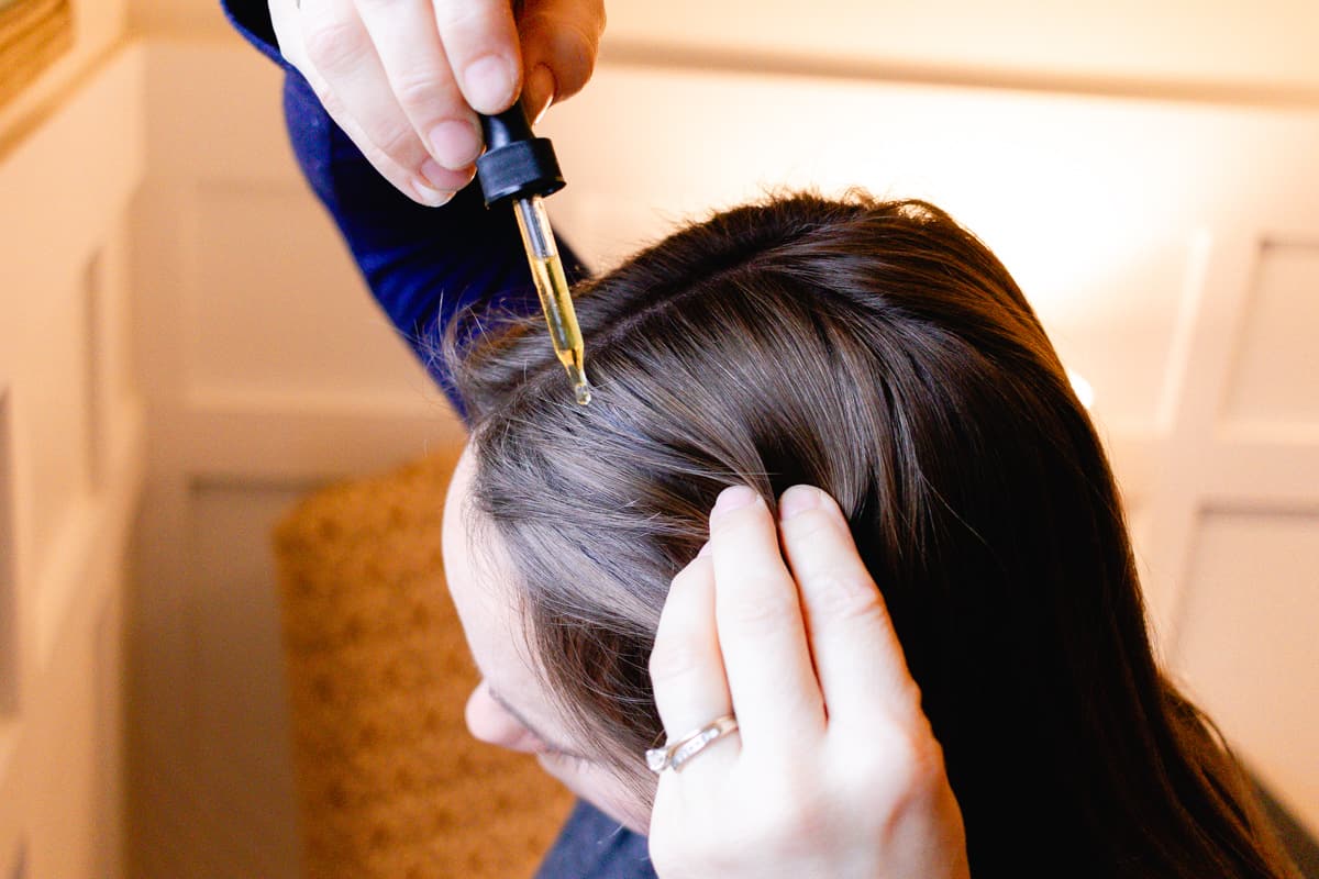Dropping homemade hair oil onto the scalp for a weekly hair oiling.