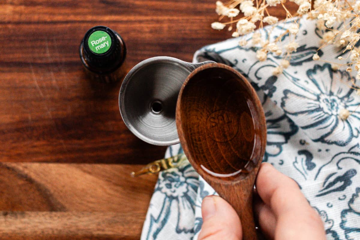 Adding the jojoba oil to the small container.